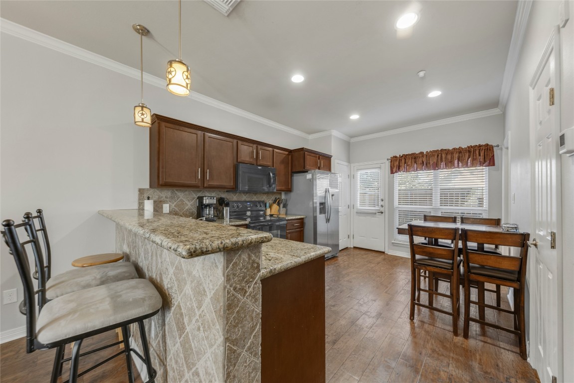 a kitchen with stainless steel appliances granite countertop a table chairs sink and cabinets