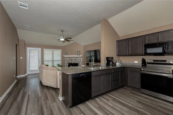 a kitchen with stainless steel appliances granite countertop wooden cabinets a sink dishwasher a stove and a refrigerator