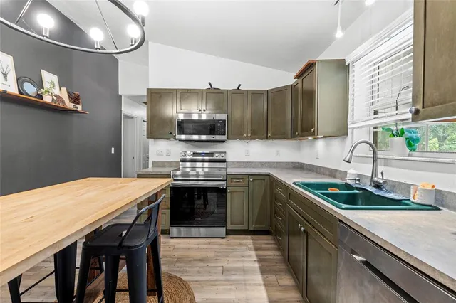 a kitchen with stainless steel appliances granite countertop a sink dishwasher a stove a microwave oven with a dining table and chairs