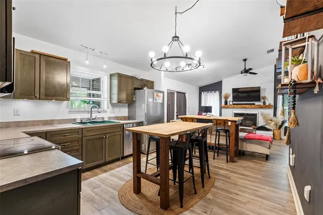 a kitchen with stainless steel appliances granite countertop a stove a refrigerator a kitchen island a dining table and chairs with wooden floor