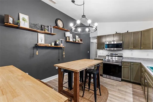 a kitchen with stainless steel appliances granite countertop a sink a stove a refrigerator with a dining table and chairs