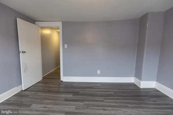 a view of an empty room with wooden floor and closet