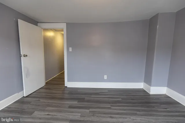 a view of an empty room with wooden floor and closet