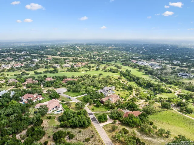 an aerial view of residential houses with outdoor space and trees