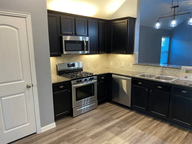 a kitchen with stainless steel appliances granite countertop a stove a sink and a refrigerator