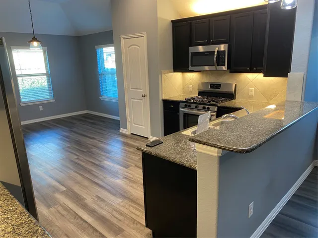 a kitchen with granite countertop stainless steel appliances and wooden cabinets