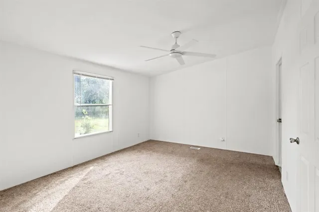 an empty room with a window and a fan