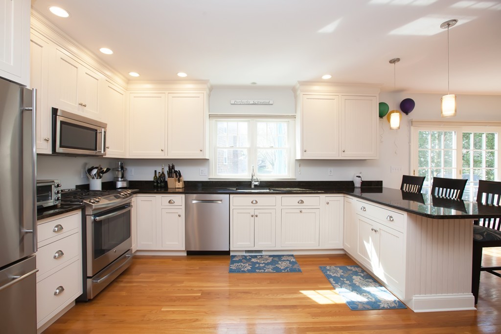 44 Kenneth Road Scituate, MA 02066 - Photo 11 of 30 a kitchen with stainless steel appliances granite countertop a stove top oven a sink a window and white cabinets