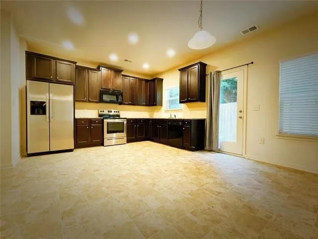 a large kitchen with a refrigerator a stove top oven a sink and dishwasher