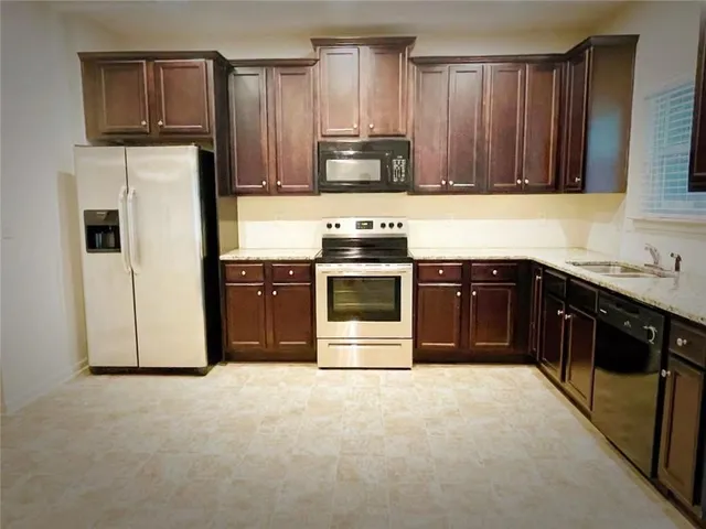 a kitchen with stainless steel appliances granite countertop a stove a sink and a refrigerator with wooden cabinets