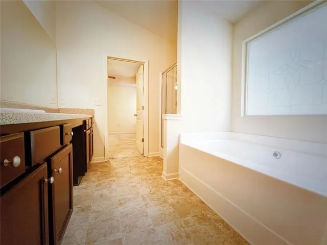 a spacious bathroom with a tub sink and mirror
