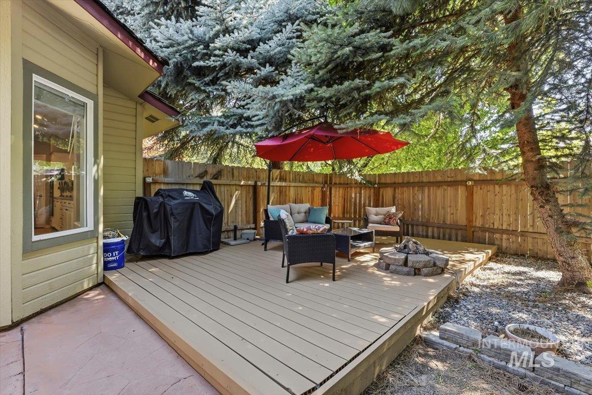 8001 West Innsbrook Court Boise, ID 83704 - Photo 34 of 39 Expansive backyard featuring a multi-level deck, a built-in fire pit, privacy fencing, and mature trees providing natural shade