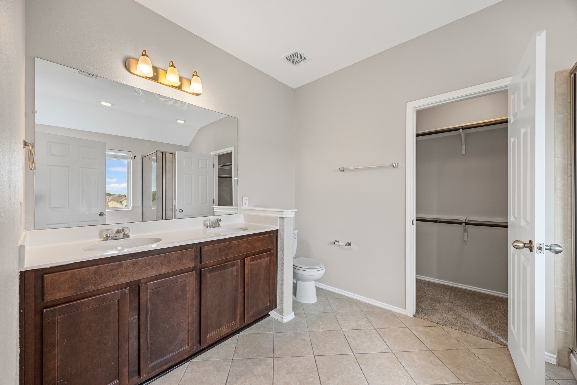 139 Diamondback Cove Buda, TX 78610 - Photo 8 of 15 a spacious bathroom with a double vanity sink a mirror and a bathtub