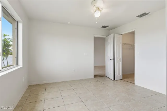 an empty room with a chandelier fan and windows