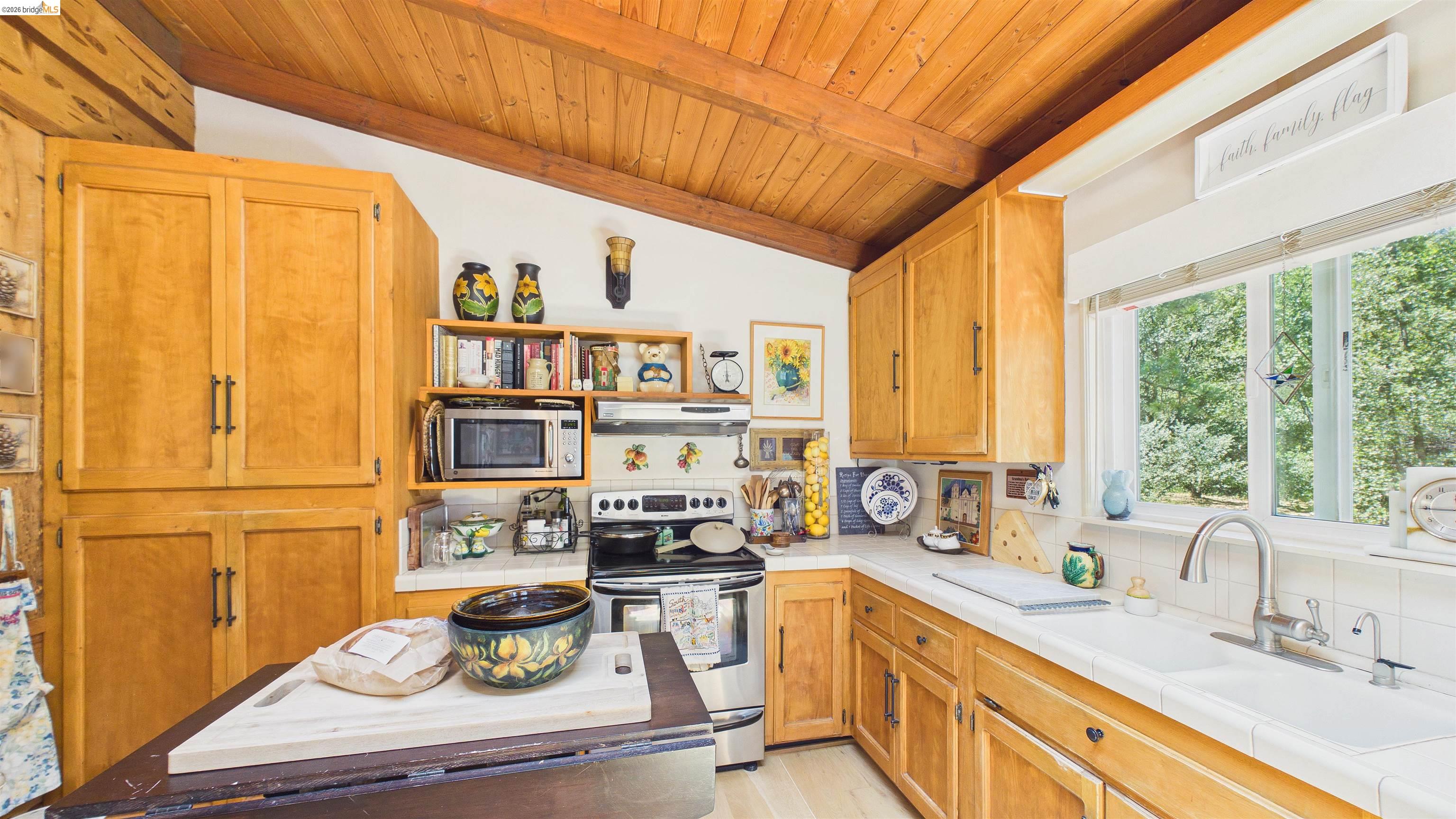 18102 Mt Eaton Road Tuolumne, CA 95379 - Photo 10 of 44 Kitchen featuring wood cabinetry, white tile countertops, stainless steel appliances, a double basin sink, and wood-finish ceiling with exposed beams