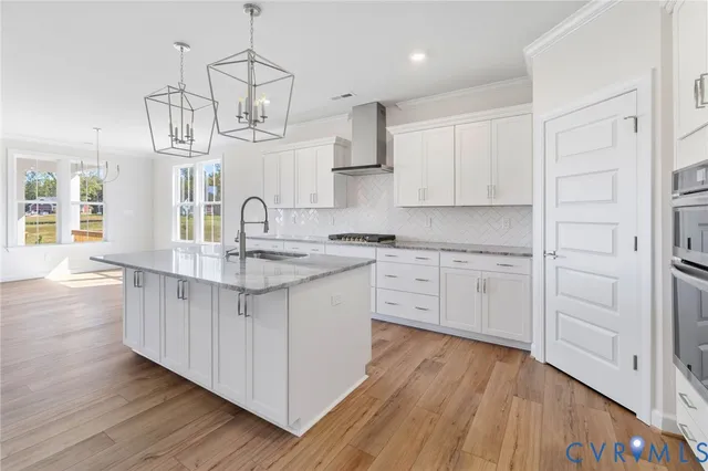 a kitchen with kitchen island granite countertop wooden floors and white cabinets