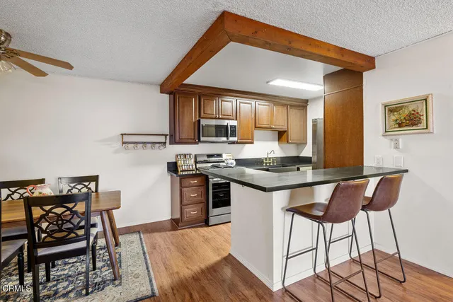 a kitchen with stainless steel appliances granite countertop a stove top oven a sink a dining table and chairs with wooden floor