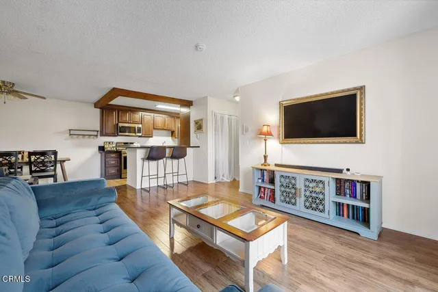 a living room with furniture a flat screen tv and kitchen view