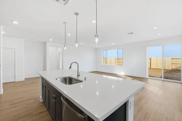 a large room with kitchen island a sink wooden floor and a large window
