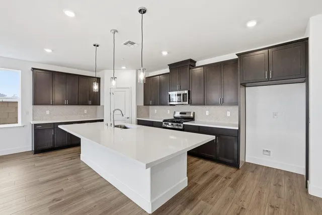 a large kitchen with stainless steel appliances a large counter top a sink a stove and a refrigerator