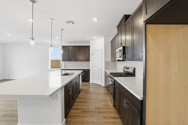 a large kitchen with stainless steel appliances granite countertop a stove a sink and a refrigerator