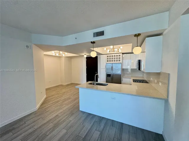 a large kitchen with a sink and wooden floor