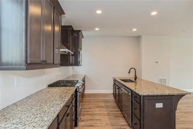 a kitchen with granite countertop stainless steel appliances sink stove refrigerator and microwave