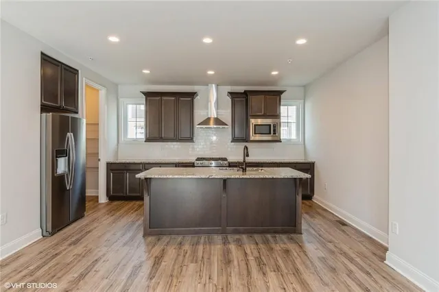 a large kitchen with wooden floor and stainless steel appliances