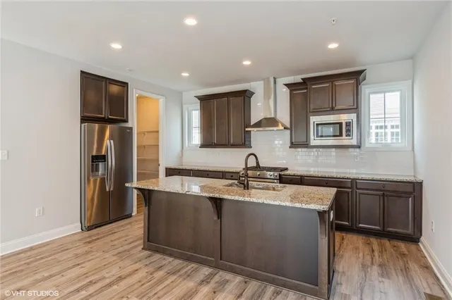 a kitchen with stainless steel appliances granite countertop a sink dishwasher stove and refrigerator with wooden floor