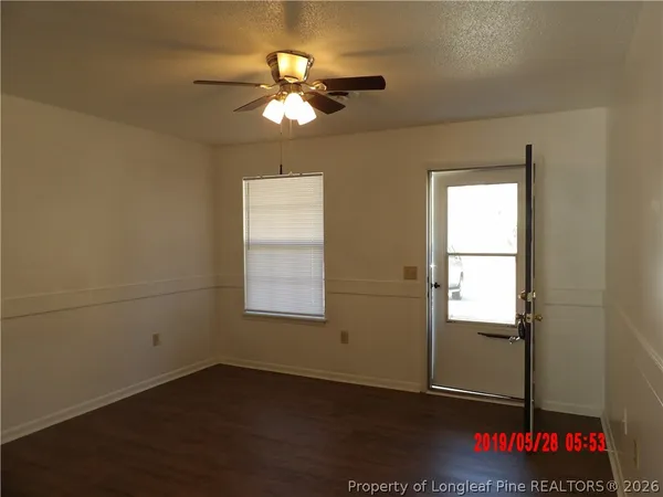 an empty room with wooden floor fan and window
