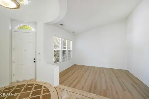a view of an empty room with window and wooden floor