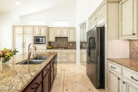 a kitchen with kitchen island granite countertop a sink stove and refrigerator