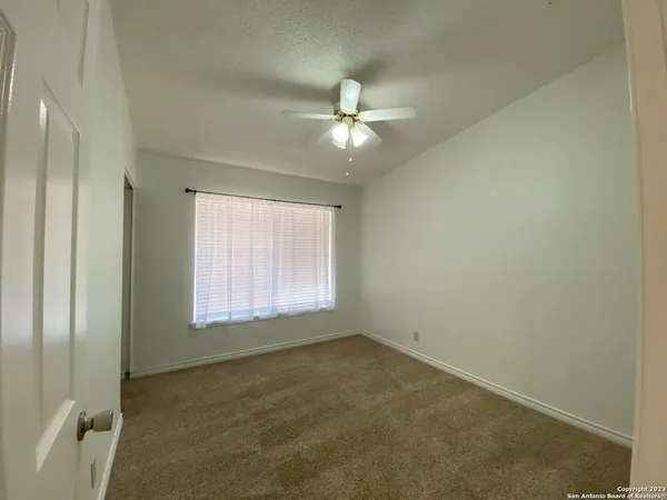 an empty room with a window and a fan