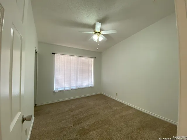 an empty room with a window and a fan