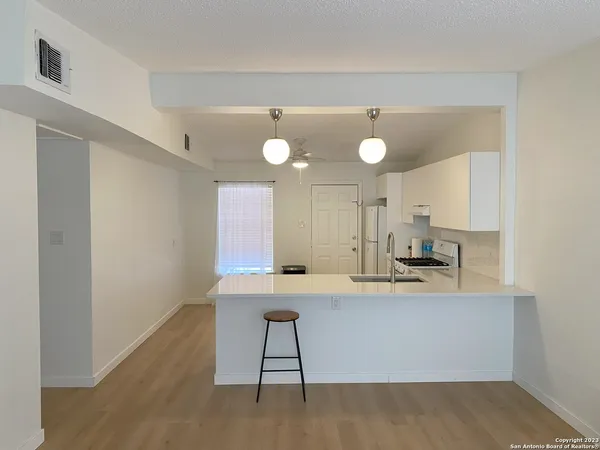 a view of a kitchen with kitchen island a sink wooden floor and counter space