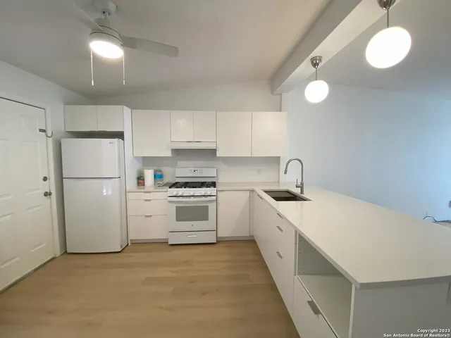 a kitchen with a sink a stove a refrigerator and white cabinets