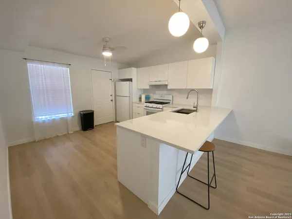 a kitchen with kitchen island a stove a sink cabinets and wooden floor
