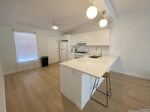 a kitchen with kitchen island a stove a sink cabinets and wooden floor