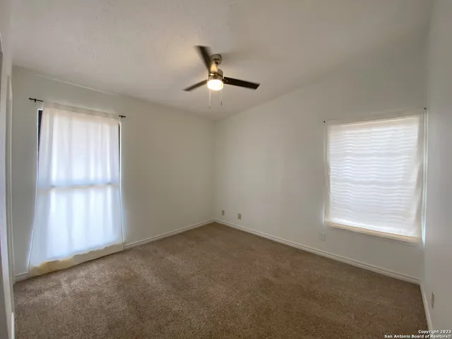 an empty room with a window and a fan