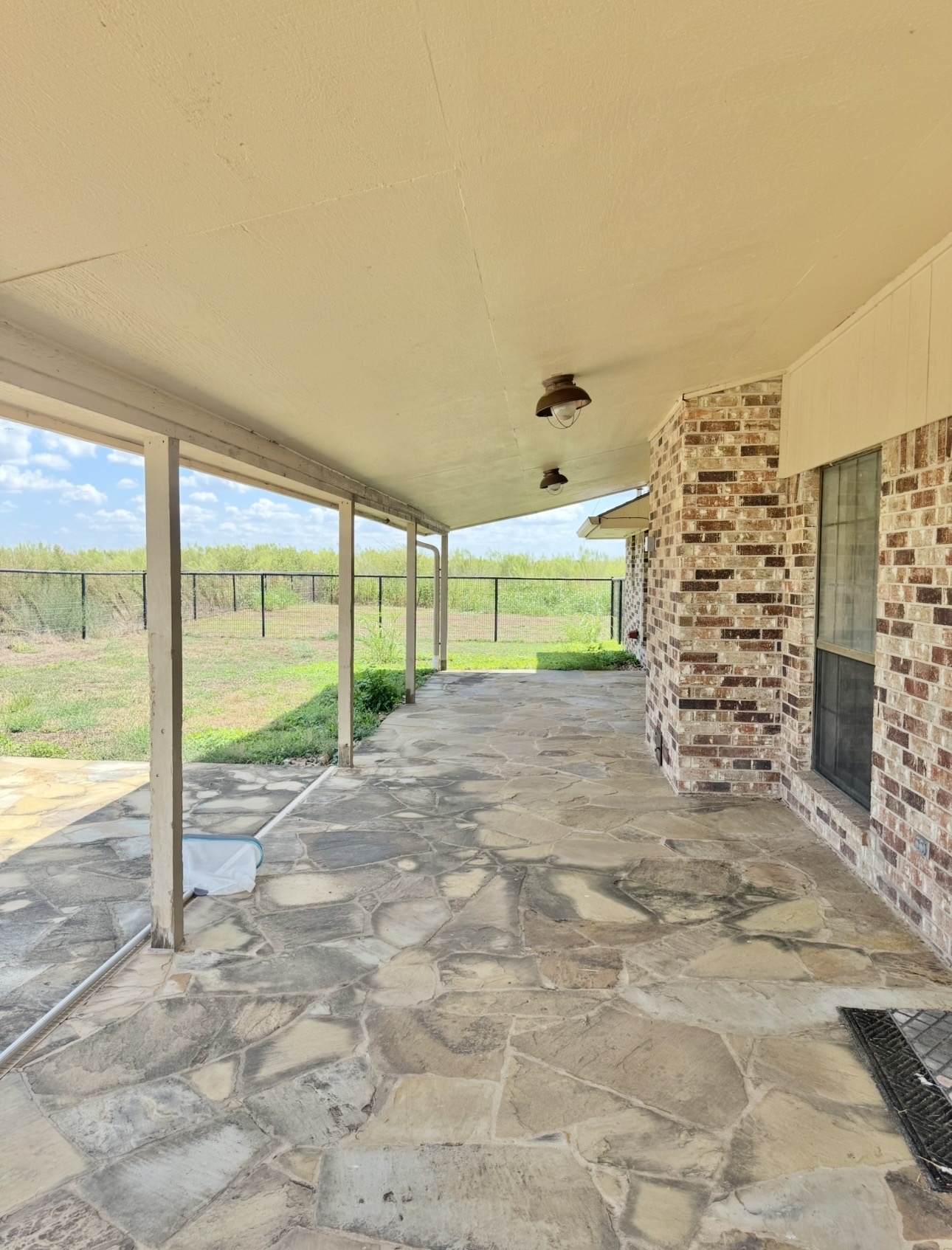18512 Carlson Lane Elgin, TX 78621 - Photo 25 of 29 A spacious covered flagstone patio overlooks the fenced yard and open green pastures.