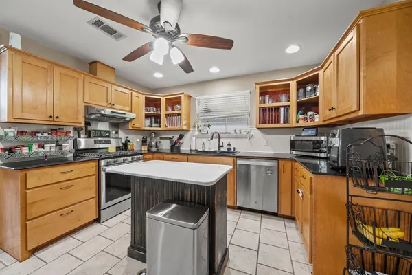 a kitchen with stainless steel appliances granite countertop a sink a stove and cabinets