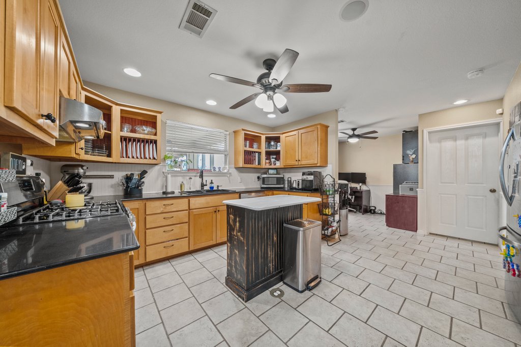 1100 Martindale Falls Road Martindale, TX 78655 - Photo 5 of 31 Kitchen with stainless steel appliances, a center island, exhaust hood, open shelves, and dark stone countertops