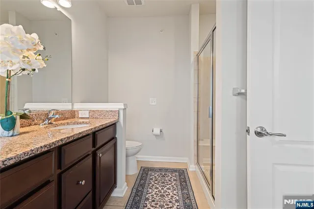a bathroom with a granite countertop sink a toilet and a mirror
