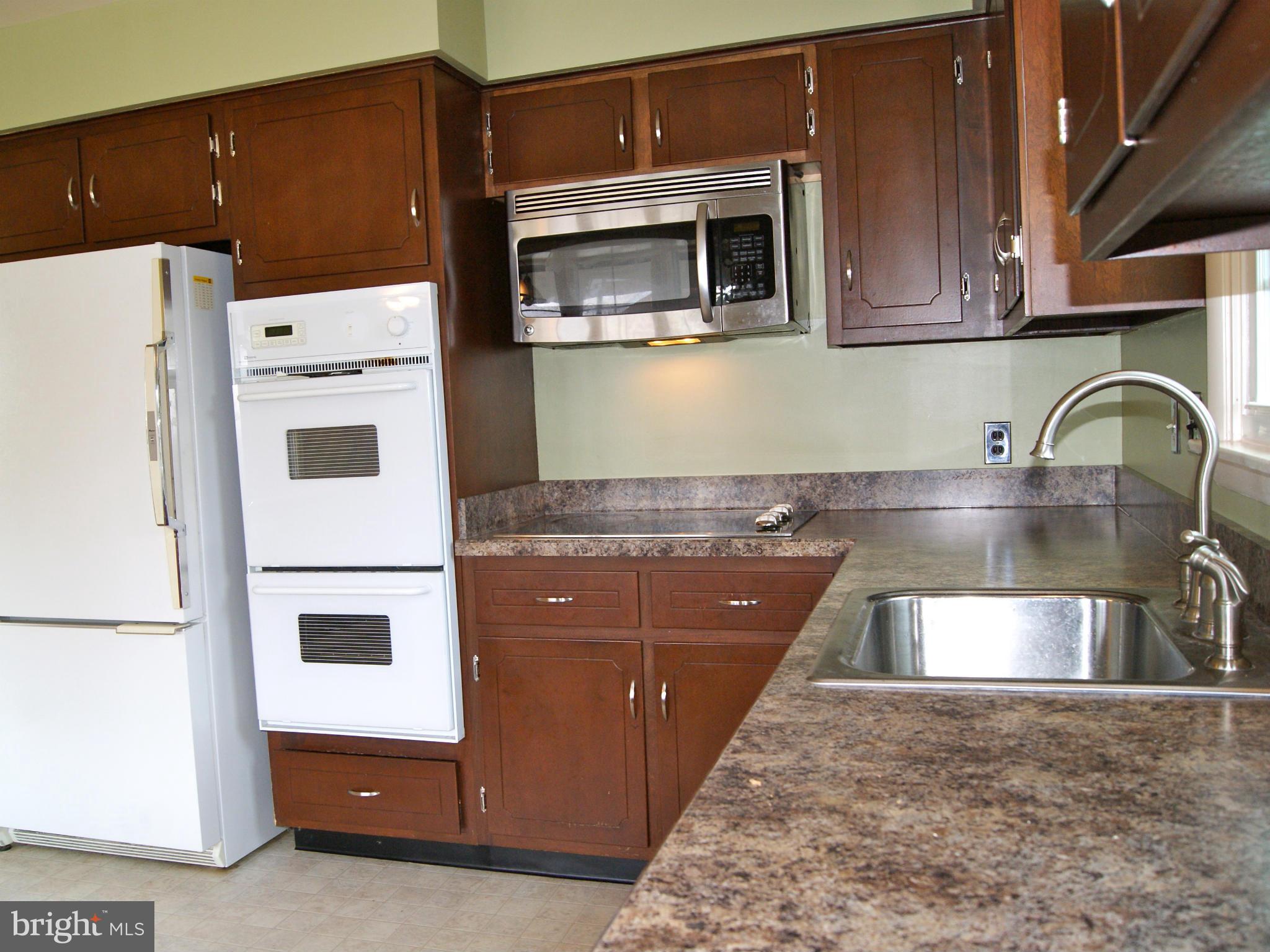 9221 Cornflower Road Baltimore, MD 21236 - Photo 12 of 25 a kitchen with stainless steel appliances granite countertop a stove a microwave and a refrigerator