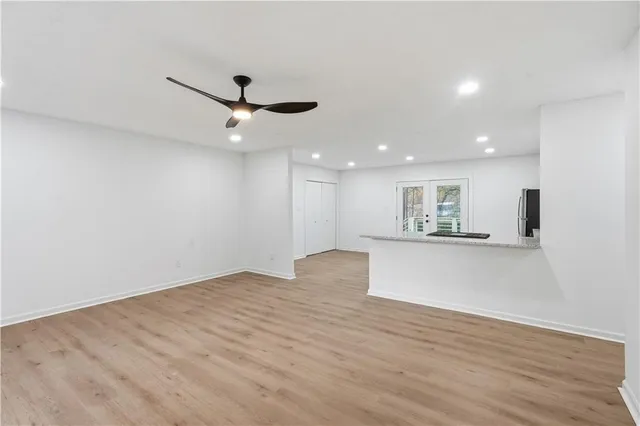 a view of an empty room with wooden floor and a ceiling fan