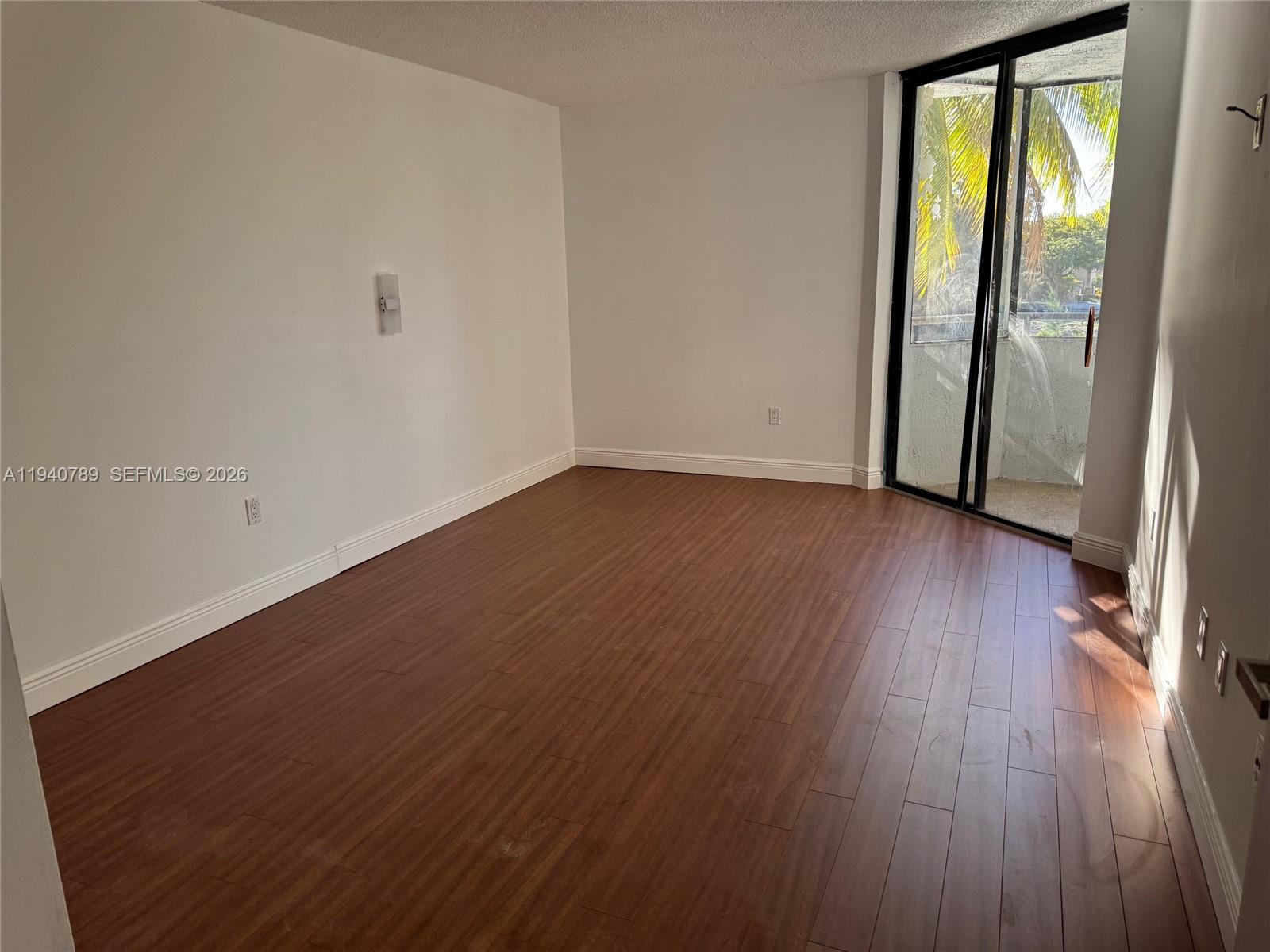 8335 Southwest 152nd Avenue, Unit B309 Miami, FL 33193 - Photo 15 of 26 an empty room with wooden floor and sliding door