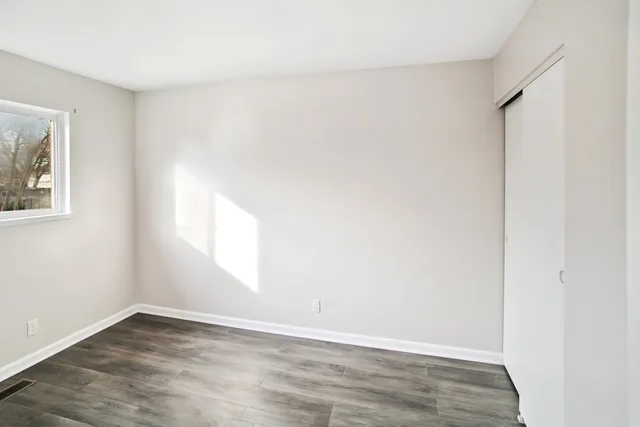 an empty room with wooden floor and windows