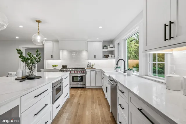 a kitchen with kitchen island a dining table chairs stove and white cabinets