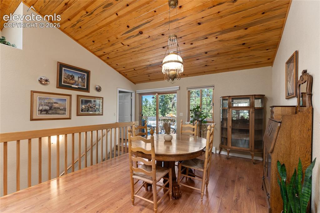 657 Spring Valley Drive Divide, CO 80814 - Photo 10 of 43 Vaulted wood-paneled ceiling with an overhead light fixture, wood-finish flooring, and a railing with vertical balusters
