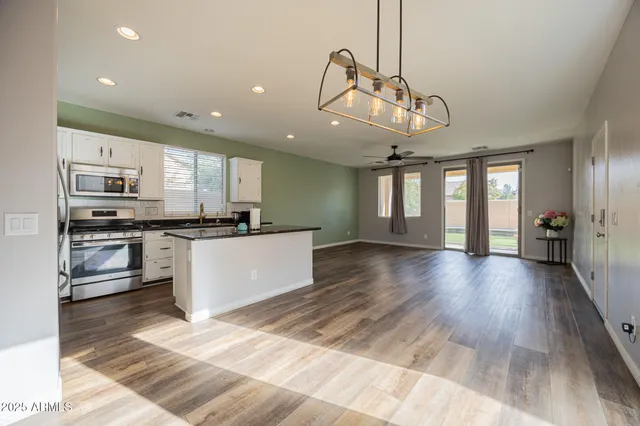 a kitchen with stainless steel appliances granite countertop a refrigerator a sink dishwasher a stove and white cabinets with wooden floor